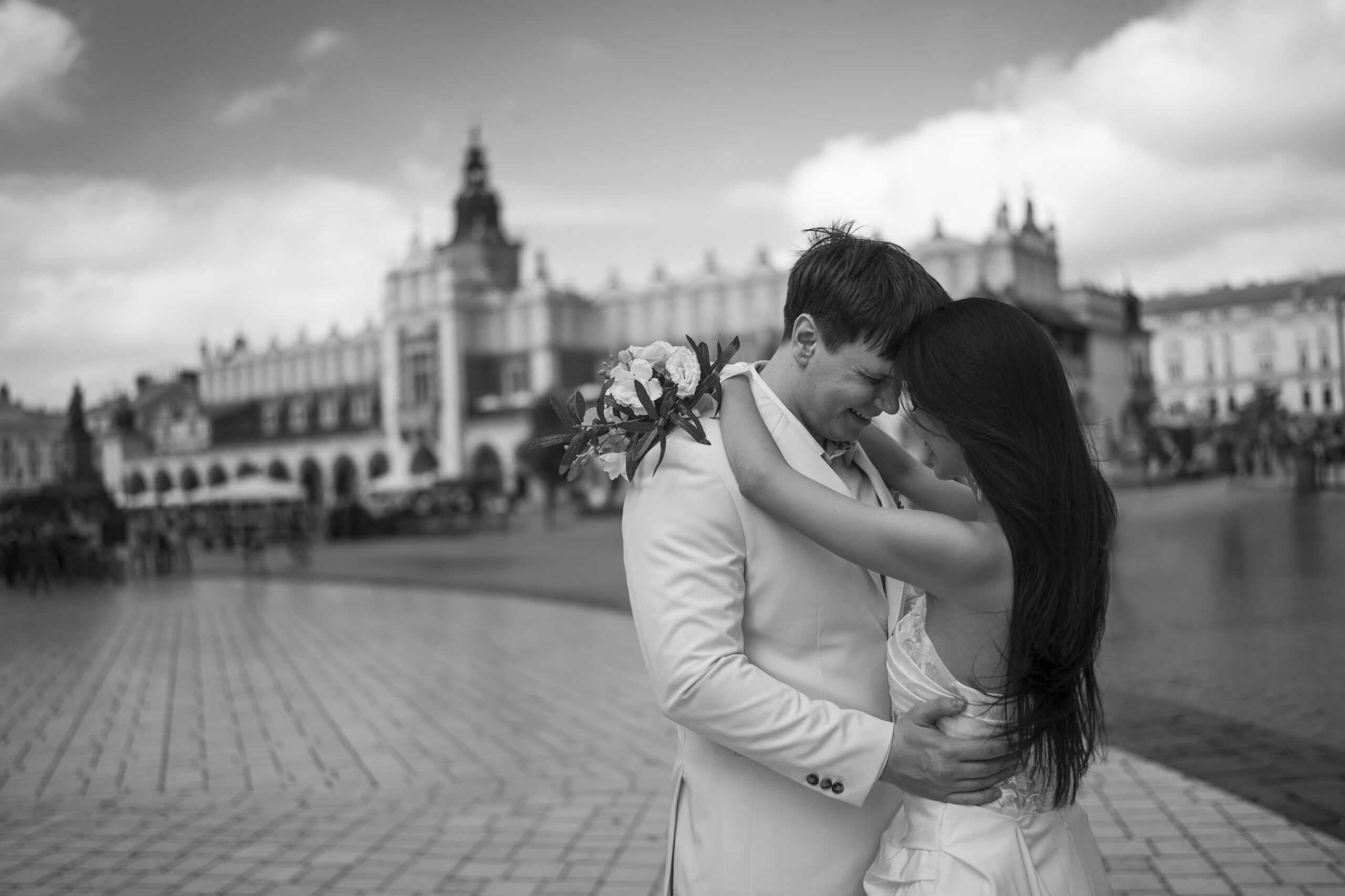 Para młoda w objęciach i uśmiechu w obiektywie fotografa ślubnego