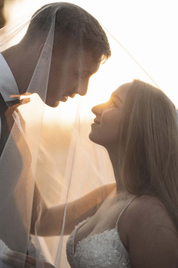 Fotograf ślubny Dąbrowa Górnicza – romantyczne ujęcie pary młodej pod welonem w złotym świetle zachodzącego słońca.