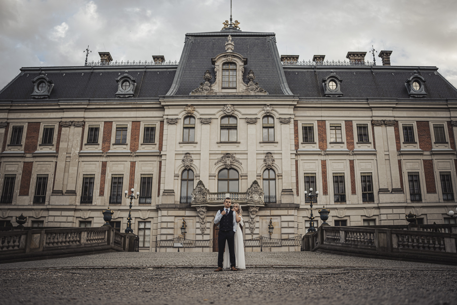 Fotograf na wesele w Gliwicach – romantyczny portret pary młodej przed historyczną budowlą.