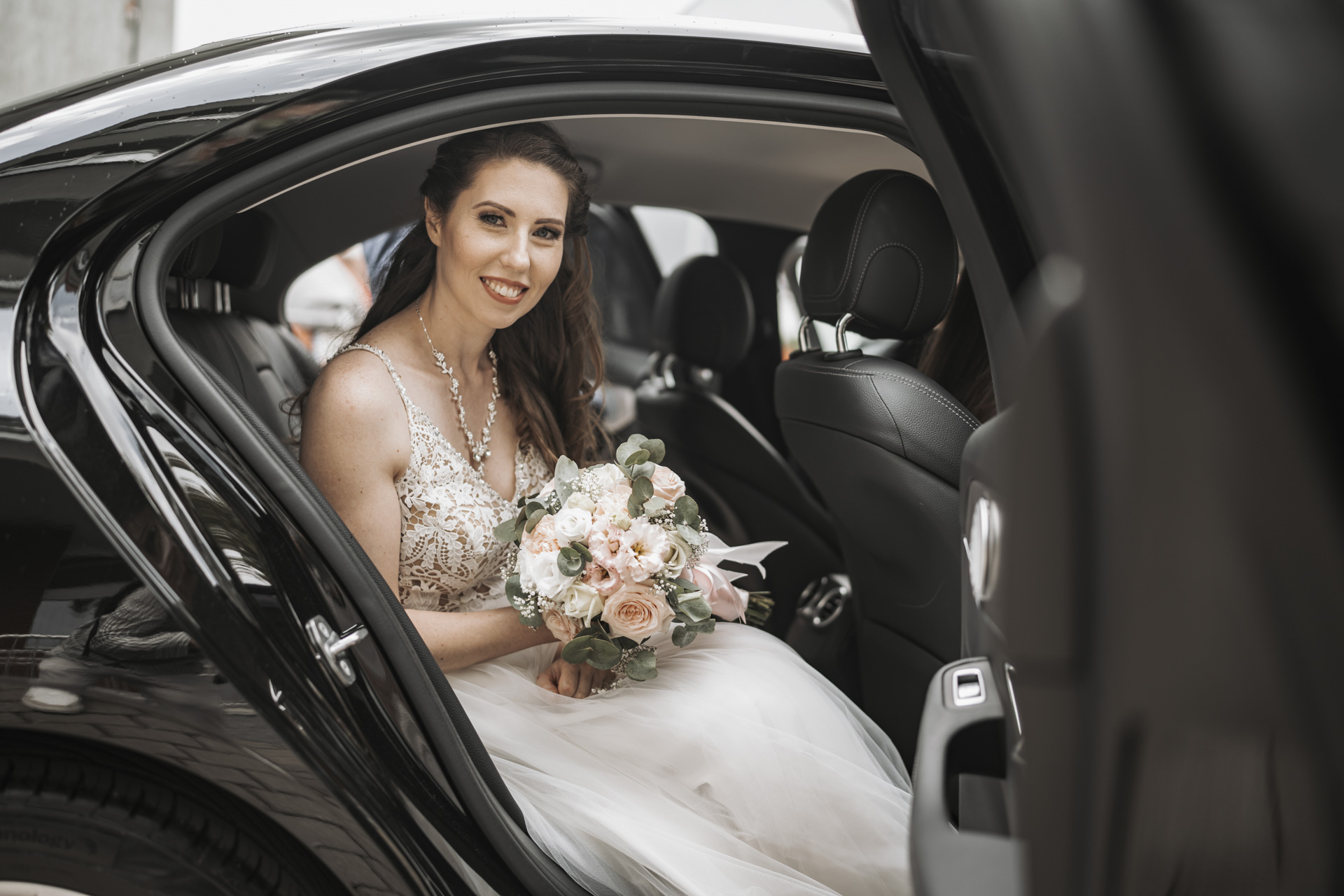 Fotograf weselny Siemianowice Śląskie – uśmiechnięta panna młoda w luksusowym aucie przed ceremonią.