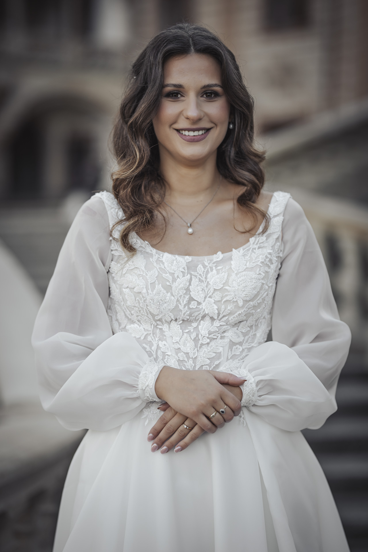 Fotografia ślubna Piekary Śląskie – portret uśmiechniętej panny młodej w koronkowej sukni z długimi rękawami.