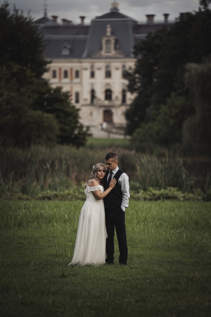 Fotografia ślubna Sosnowiec – para młoda stojąca na trawniku przed majestatycznym, zabytkowym pałacem.