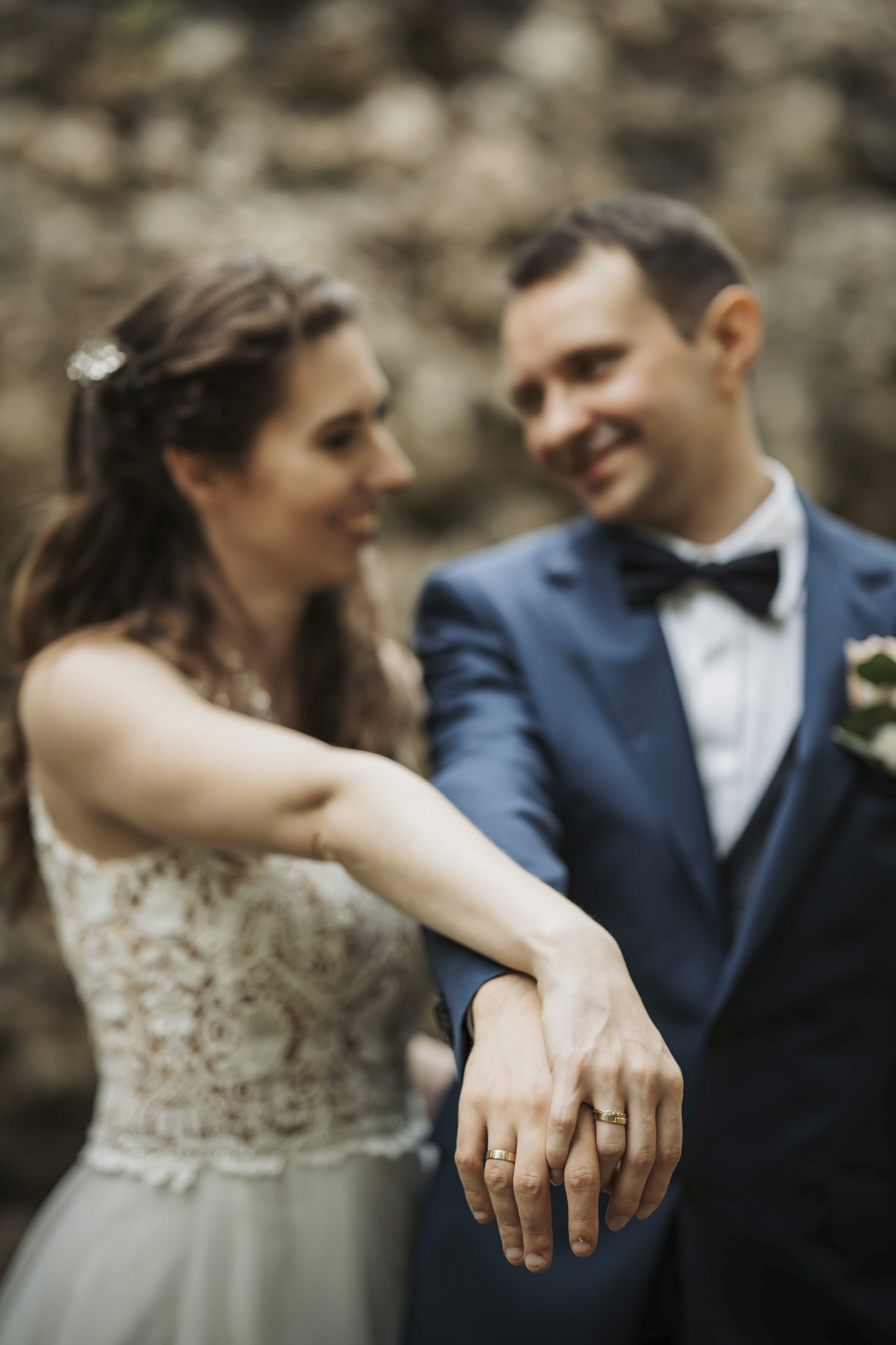 Fotograf ślubny Zabrze – zbliżenie na dłoń panny młodej z pierścionkiem zaręczynowym na tle całującej się pary.