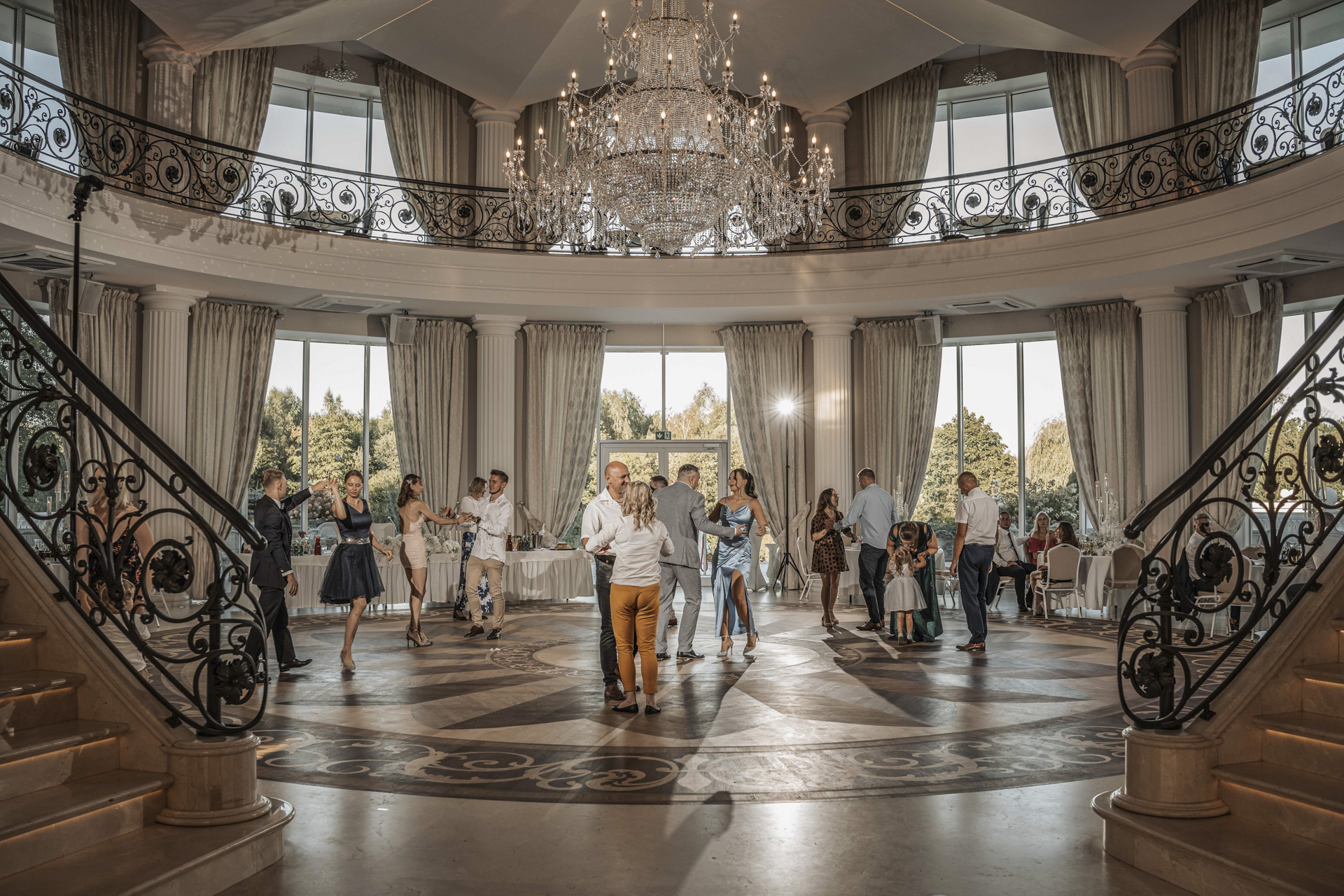 Reportaż ślubny Bytom – Eliza i Romek z gośćmi w eleganckiej sali weselnej z żyrandolami.