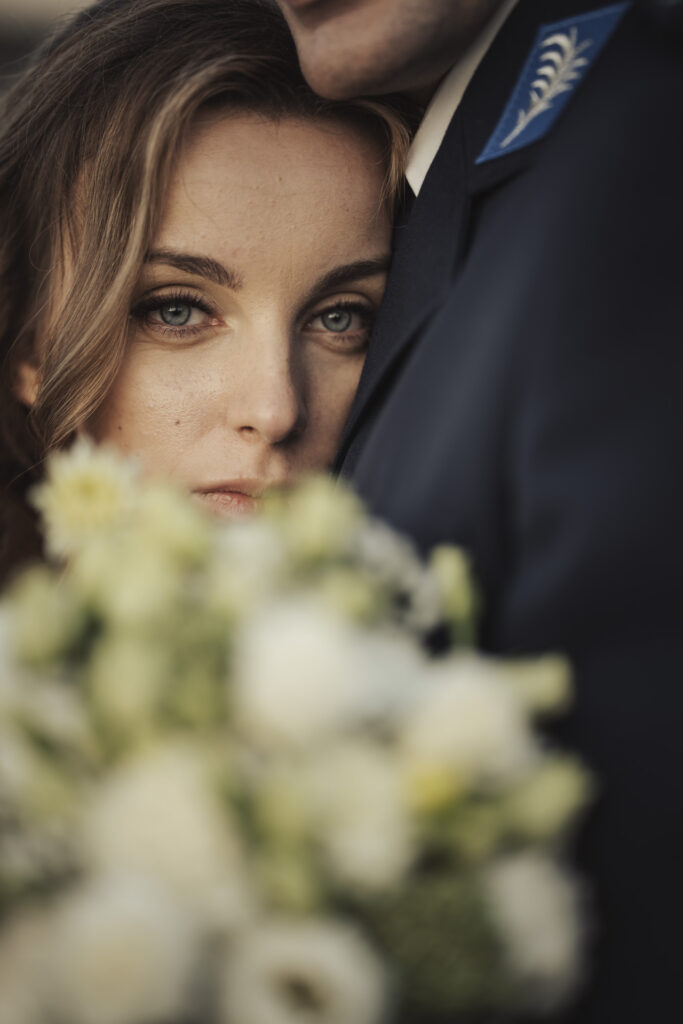 Sesja ślubna Świętochłowice – intymny portret panny młodej wtulonej w ramie pana młodego, z bukietem kwiatów na pierwszym planie.